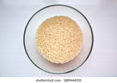 A Big Bowl Of White Rice Photo From The Top. Processed Raw Rice For Cooking. Transparent Bowl With Yellow Rice Grits.