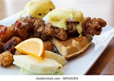 Big Breakfast Special At Restaurant With Fried Chicken And Waffles Under Eggs Benedict And A Side Of Potato Tater Tots