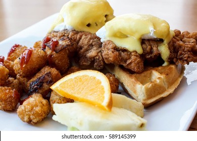 Big Breakfast Special At Restaurant With Fried Chicken And Waffles Under Eggs Benedict And A Side Of Potato Tater Tots