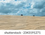 A big bright yellow sand dune on the background of bright cloudy sky. Something like a hieroglyph on the surface. Stockton Sand Dunes near the coast, Worimi Regional Park, Anna Bay, Australia. 