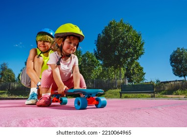 Big Brother Play With Little Sister At Skatepark Wearing Helmet Pushing Her On The Ramp