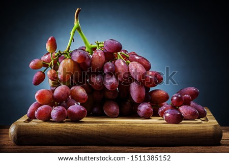 big  bunch of rose grape on wooden cutting board and black gradient background