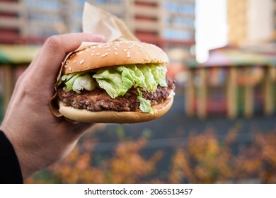 big burger in a man's hand on a blurred background