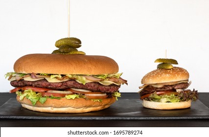 The Big Burger And The Normal Burger. Craft Beef Burger On Stone Table On White Background. Big  And Small American Burgers.  