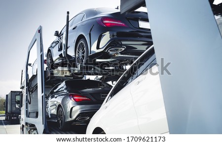 Big car carrier truck of new luxury sport german cars  delivery to dealership . truck of new powerful  new vehicles. Car detailing : Glass coating Automotive industry buy  rent  shipping background.