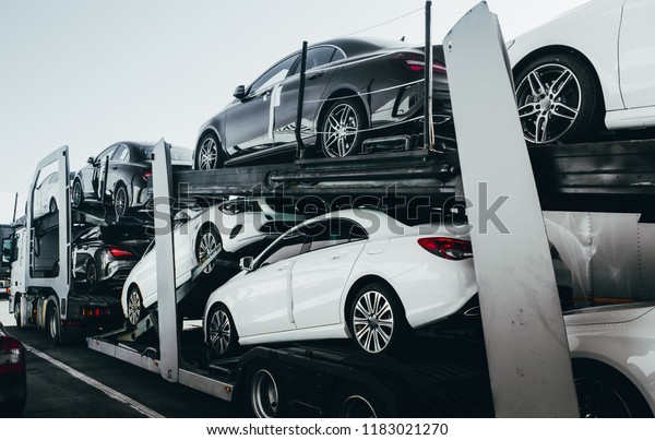 Big car carrier truck of new luxury sport \
german cars for batch delivery to dealership . Full load transport\
truck of new powerful new vehicles. Automotive industry  rent \
shipping background.