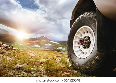 Big car wheel on mountains and sunset backdrop. Offroad 4x4 concept