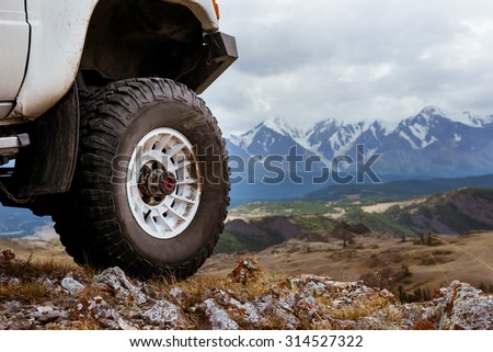 Big car wheel is standing on the rocks on mountain backdrop. Altay mountains, Siberia, Russia