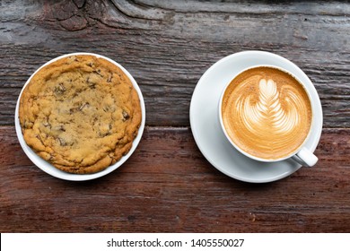 Big Chocolate Chip Cookie On A Plate With A Latte On A Wood Table