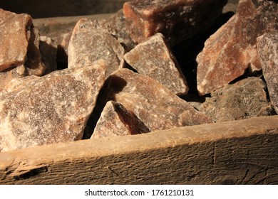 Big Chunks Of Grey Rose Colored Rock Salt Displayed In A Old Wooden Log Under Tungsten Lighting