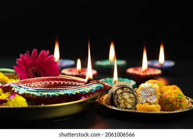 Big Clay Diya Deep Lit With Indian Mithai Laddu, Meetha Laddoo, Burfi, Anjeer Roll, Red Flower And Small Dia. Theme For Diwali Pooja, Navratri, Dussehra Puja, Deepawali Or Shubh Deepavali