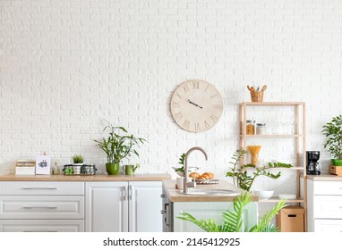 Big Clock Hanging On White Brick Wall In Kitchen