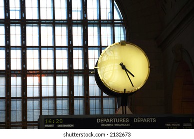 Big clock inside a train station on top of the time table