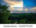 big clouds at sun setting over a forest