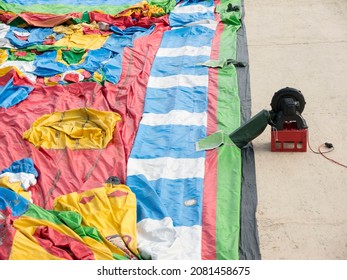 Big Color Fabric Trampoline Castle Laying Down On Ground Start Inflating With Electric Air Blower On Plastic Box Side View