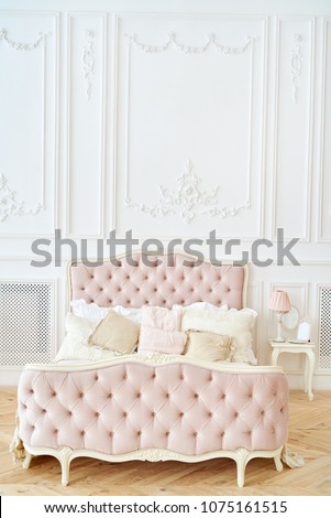 Big comfortable royal bed with pillows in elegant bedroom interior, copy space. Honeymoon suite, free space. Female bedroom in pink and white colors. Luxury bed in romantic style. Boudoir