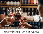 Big company people clinking glasses with red, rose and white wine on blurred cellar background. Men and women cheers with alcohol drink, closeup