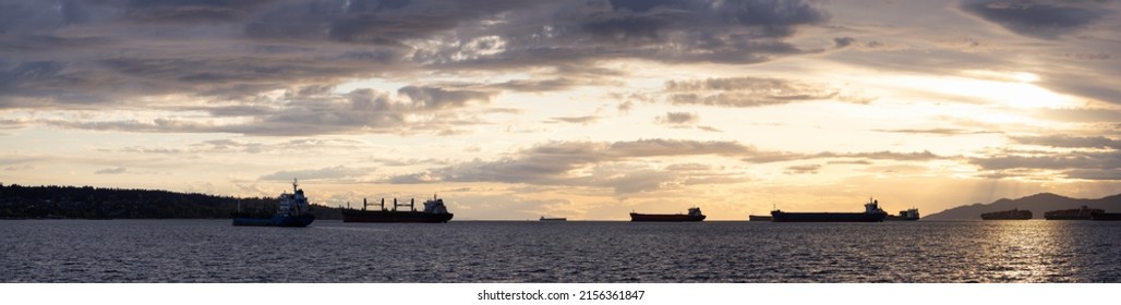 Big Container Ship parked in Burrard Inlet on the West Coast of Pacific Ocean. Colorful cloudy sunset sky. Vancouver, British Columbia, Canada. Panorama