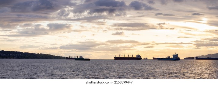 Big Container Ship parked in Burrard Inlet on the West Coast of Pacific Ocean. Colorful cloudy sunset sky. Vancouver, British Columbia, Canada. Panorama