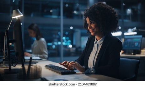 In Big Corporate Office in the Evening: Portrait of African American Female Manager Using Computer, Businesspeople and Experts Working Around Her, Analysing Statistics, Commerce Data, Marketing Plans.