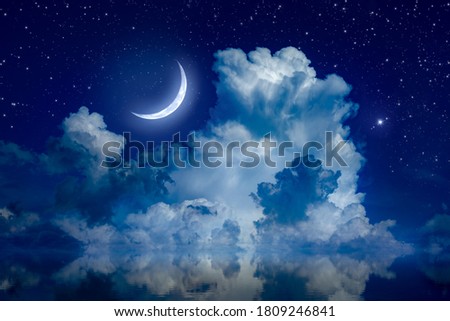 Big crescent moon and clouds in night starry sky is reflected in calm sea. Silence, calmness and serenity. Elements of this image furnished by NASA