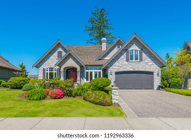 Big custom made luxury house with nicely landscaped and trimmed front yard and driveway to garage in the suburbs of Vancouver, Canada.