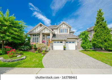 Big custom made luxury house with nicely landscaped and trimmed front yard and long driveway in the suburbs of Vancouver, Canada.
