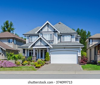 Big custom made luxury house with nicely trimmed and landscaped front yard and driveway to garage in the suburb of Vancouver, Canada.