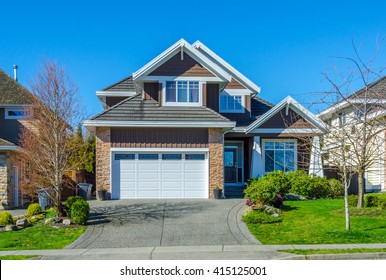 Big custom made luxury house, house entrance with nicely trimmed and landscaped front yard in the suburbs of Vancouver, Canada.
