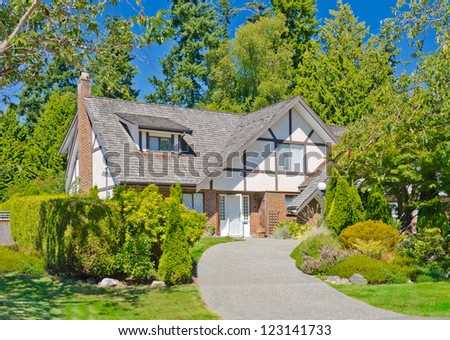 Big custom made luxury house with long curved driveway and nicely landscaped front yard in the suburbs of Vancouver, Canada.