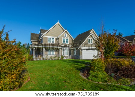 Big custom made luxury house at fall, autumn season, time with nicely landscaped and trimmed front yard in the suburbs of Vancouver, Canada.