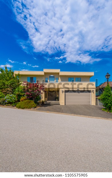 Big custom made luxury house with nicely\
landscaped and trimmed front yard and driveway to garage in the\
suburbs of Vancouver,\
Canada.