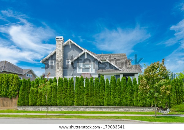 Big custom made luxury\
house behind nicely trimmed green fence  in the suburbs of\
Vancouver, Canada.