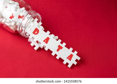 Big data analysis, unstructured database processing metaphor, large volume of  white puzzle jigsaws with alphabets pouring from bottle combine word DATA on red fabric background with copy space.