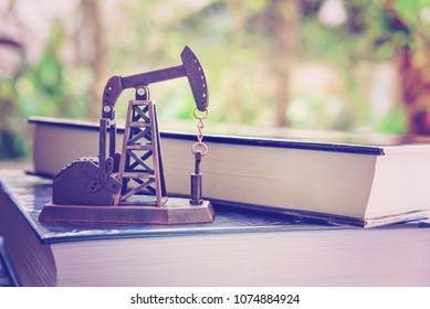 Big data and data mining concept : Oil or petroleum pump jack on two thick books, depicts the collective data or extraction technic that are performed on large sets / volume of data, uncovering info.