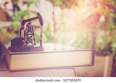 Big data and data mining concept : Oil or petroleum pump jack on two thick books, depicts the collective data or extraction technic that are performed on large sets / volume of data, uncovering info.