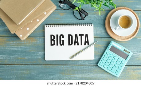 Big Data Text With A Person Holding A Pen On A Wooden Desk.