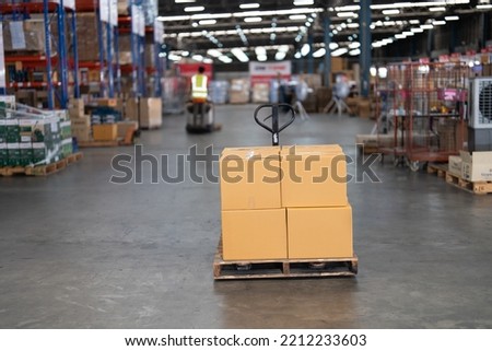 In the big depot storage ware house common use wooden pallet and hand pallet truck carry goods distribute to storage shelf
