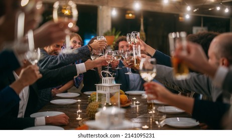 Big Dinner Party with a Small Crowd of Multiethnic Diverse Friends Celebrating at a Restaurant. Beautiful Happy Hosts Propose a Toast and Raise Wine Glasses while Sitting at a Table in the Evening. - Powered by Shutterstock