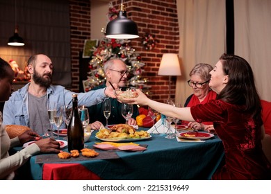 Big Diverse Family Having Christmas Dinner, Eating Traditional Food At Festive Table, Man Passing Woman Bowl With Dish. People Celebrating Xmas Holidays With Parents At Home Party