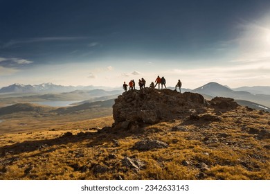 Big diverse group of hikers silhouettes stands at mountain top and looks at sunset - Shutterstock ID 2342633143