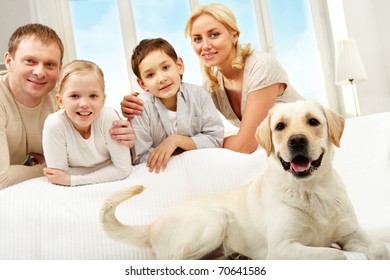 A Big Dog Lying On Sofa, A Family Of Four Standing Behind