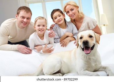 A Big Dog Lying On Sofa, A Family Of Four Standing Behind