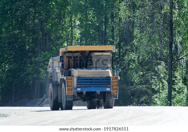A big dump truck is moving along the\
highway. In the frame of the huge wheels and the lower part of the\
car (without the ability to determine\
brand).