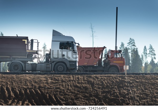 big dump trucks white and red go on the\
constructed highway.
