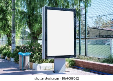 Big Empty Billboard In Black Frame With Empty White Mockup Space On Sidewalk Of City Street In Summer Day