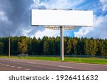 Big empty mockup Billboard along a highway with forest on background of blue sky with beautiful clouds.