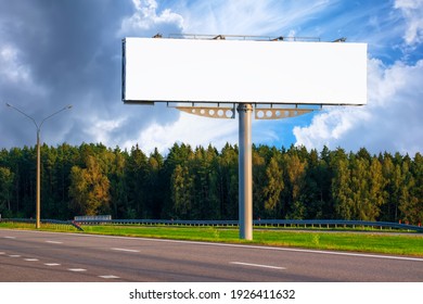 Big empty mockup Billboard along a highway with forest on background of blue sky with beautiful clouds.