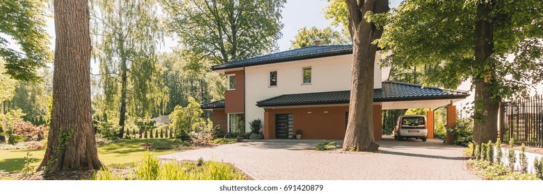 Big Entrance With Stone Pathway To White And Brown House