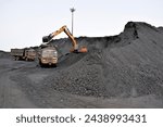 Big Excavator machine filling coal in trucks for transportation from the bulk cargo of coal at port, for thermal power plants. 